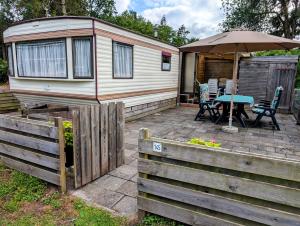 a tiny house with a table and an umbrella at Stacaravan Il Piccolo Nido in Bosrijke Omgeving, Rust & Natuur in Drenthe in Eext