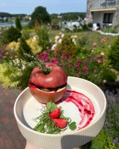 a person holding a hot dog on a plate with strawberries at Dom Wczasowy Stenka in Gowidlino