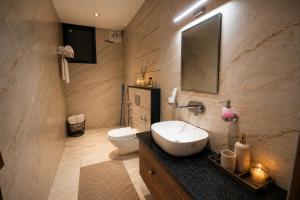 a bathroom with a sink and a toilet and a mirror at Minara Meadows Kasauli in Dharampur