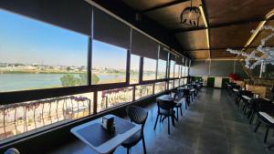 a restaurant with tables and chairs and large windows at Sky Airport Hotel - فندق سما المطار in Al Mawşil