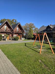 a swing set in a yard in front of a house at Domki Relaksowa in Nowęcin