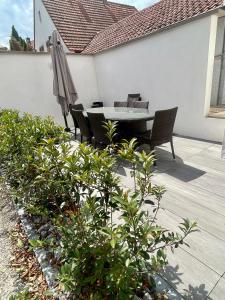 a patio with a table and chairs and an umbrella at La Maison Caroline in Surbourg
