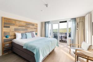 a bedroom with a large bed and a balcony at Strandhotel Zoutelande in Zoutelande