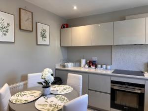 a kitchen with two tables and a counter with white cabinets at Northway Apartment's in Oxford
