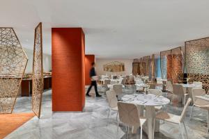 a restaurant with tables and chairs and a man walking in the background at COMO Metropolitan Bangkok in Bangkok
