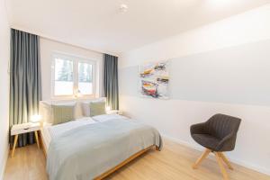 a white bedroom with a bed and a chair at Ferienwohnung Urlaubsflair in Timmendorfer Strand