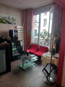a living room with a red chair and a fireplace at Hôtel Montsouris Orléans in Paris