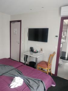 a bedroom with a bed and a desk with a tv at Hôtel Montsouris Orléans in Paris