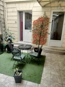 a patio with a table and chairs and a tree at Hôtel Montsouris Orléans in Paris
