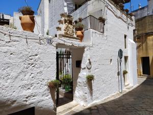 a white building with a gate and potted plants at B&B "Pulia Dimore Salentine" in Alessano