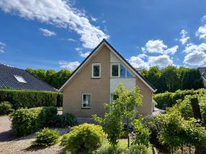 a house in a yard with bushes and trees at The Poplar Place - Spacious Comfort, Hot Tub in Private Garden in Zeewolde