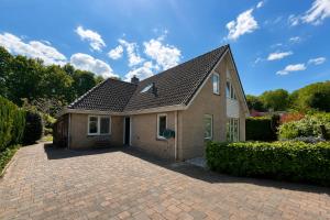 a house with a brick driveway in front of it at The Poplar Place - Spacious Comfort, Hot Tub in Private Garden in Zeewolde