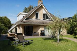 a house with chairs and a grill in the yard at The Poplar Place - Spacious Comfort, Hot Tub in Private Garden in Zeewolde