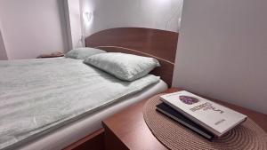 a bed with a table with a book on it at Apartma Rožman in Radenci