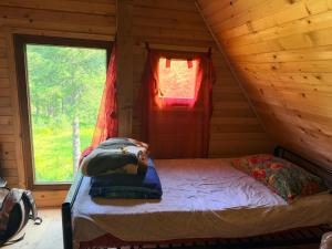 a bed in a log cabin with a window at ILDO Guesthouse in Asim Zeneli