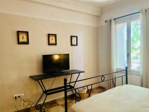 a bedroom with a bed and a television on a table at Mas des 4 fontaines in Robion en Luberon