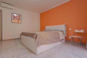 a bedroom with a bed with an orange wall at Magnifica Terrazza - Lake View & Wi-Fi in Gardone Riviera
