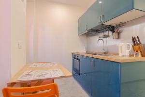 a kitchen with blue cabinets and a wooden table at Magnifica Terrazza - Lake View & Wi-Fi in Gardone Riviera