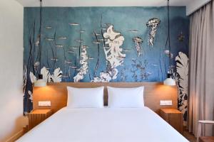 a bedroom with a bed and a painting on the wall at Kyriad Lannion-Perros-Guirec in Lannion +56 photos