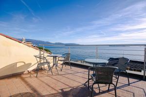 a balcony with tables and chairs and a view of the water at Magnifica Terrazza - Lake View & Wi-Fi in Gardone Riviera