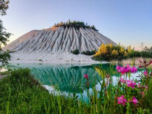 a prehistoric mound with a reflection in a body of water at RUMMU Quarry Houses in Rummu
