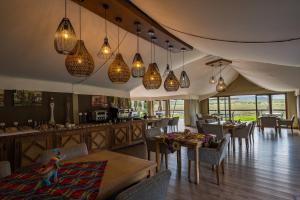 a dining room with tables and chairs and pendant lights at Tau Game Lodge in Madikwe Game Reserve