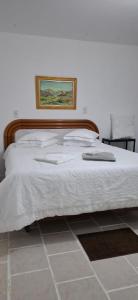 a bed with white sheets and a picture on the wall at Chacara Recanto Vale do Luar in Piraquara +23 photos