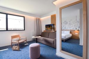 a hotel room with a couch and a bed and a mirror at Kyriad Lannion-Perros-Guirec in Lannion