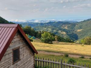 a wooden house with a fence and mountains in the background at Katun Lanista-Kolibe Bogavac in Mojkovac
