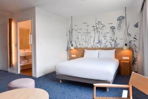 a bedroom with a white bed and a wall mural at Kyriad Lannion-Perros-Guirec in Lannion