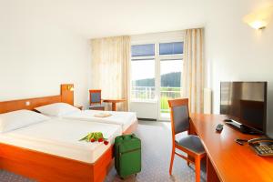 a hotel room with a bed and a desk and a computer at Terme Topolsica - Hotel Vesna in Topolšica