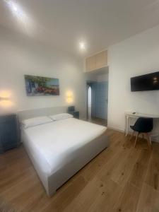 a white bedroom with a white bed and a desk at Lulù Marin Rooms in Scalea