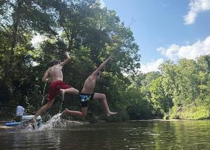 two boys jumping off a raft in the water at Cabin 2 - steps from the river! in Huntsville +16 photos