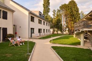 two people sitting in chairs on a lawn in front of a building at Kyriad Lannion-Perros-Guirec in Lannion
