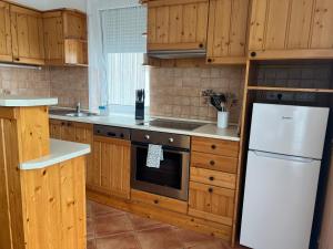 a kitchen with wooden cabinets and a white refrigerator at Johanna Apartman in Harkány