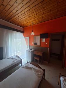 a bedroom with two beds and a desk and a window at Hotel Ira in Leptokarya