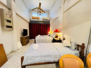 a hotel room with two beds and a television at Baan Bangrak Home in Bang Rak