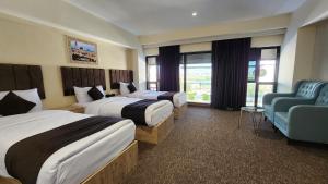 a hotel room with two beds and a chair at Sky Airport Hotel - فندق سما المطار in Al Mawşil