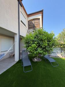 a yard with two lawn chairs and a tree at Location Vias in Vias