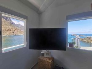 a flat screen tv in a room with two windows at Ocean front La Maresia Holiday 2 Apartments in Taganana