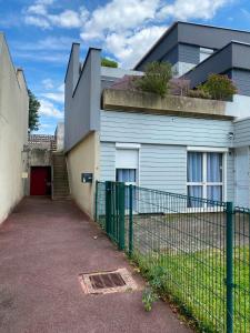 a fence in front of a house with a building at Maison Spacieuse et Confortable 100m2 avec Jardin in Val de Reuil