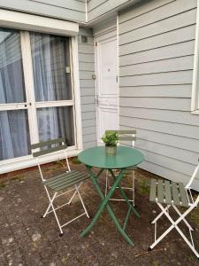 a green table and two chairs sitting outside of a house at Maison Spacieuse et Confortable 100m2 avec Jardin in Val de Reuil