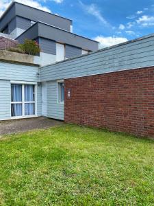 a building with a brick wall next to a yard at Maison Spacieuse et Confortable 100m2 avec Jardin in Val de Reuil +6 photos