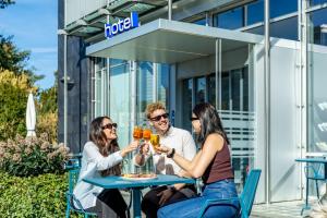 Eine Gruppe von Menschen sitzt mit Getränken an einem Tisch. in der Unterkunft Lifestyle Hotel Sedartis Lake Zurich in Thalwil