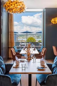 ein Restaurant mit Tischen und Stühlen und einem großen Fenster in der Unterkunft Lifestyle Hotel Sedartis Lake Zurich in Thalwil