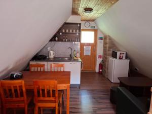 a kitchen and dining room with a wooden table and chairs at Chatka pod jaskyňou in Malužiná
