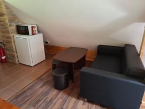 a living room with a couch and a table and a refrigerator at Chatka pod jaskyňou in Malužiná +4 photos