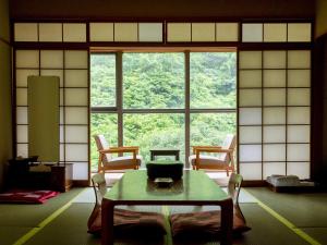 a room with a table and chairs and a large window at Okudogo Ichiyunomori in Matsuyama