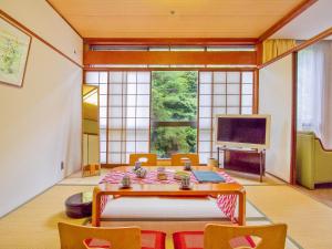 a living room with a table and chairs and a television at Okudogo Ichiyunomori in Matsuyama
