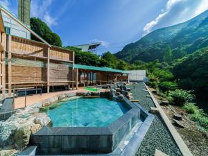 a house with a swimming pool with mountains in the background at Okudogo Ichiyunomori in Matsuyama